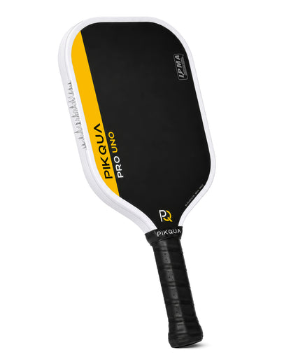 A Pikqua Pro Uno Kevlar pickleball paddle with a black face, white border with the NYC skyline, yellow accent stripe, and black wrapped handle, shown on a white background.