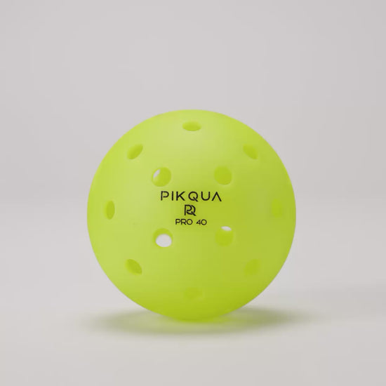 Video of a bright yellow pickleball with perforations, rotating, branded PIKQUA PRO 40, arranged on a clean white background.