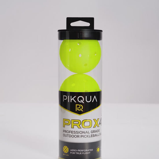 A video of a package of three bright neon yellow pickleballs in a clear cylindrical plastic case with a black lid and a black-and-yellow PIKQUA PROX4 label, photographed on a white background.